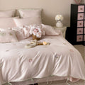 Embroidered cotton satin bedding set with decorative ribbons and floral appliqués
