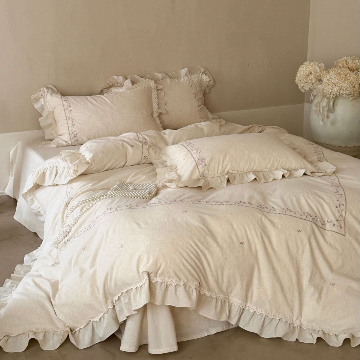 Vintage-inspired cotton bedding set with ruffles, delicate floral embroidery, and lace trim