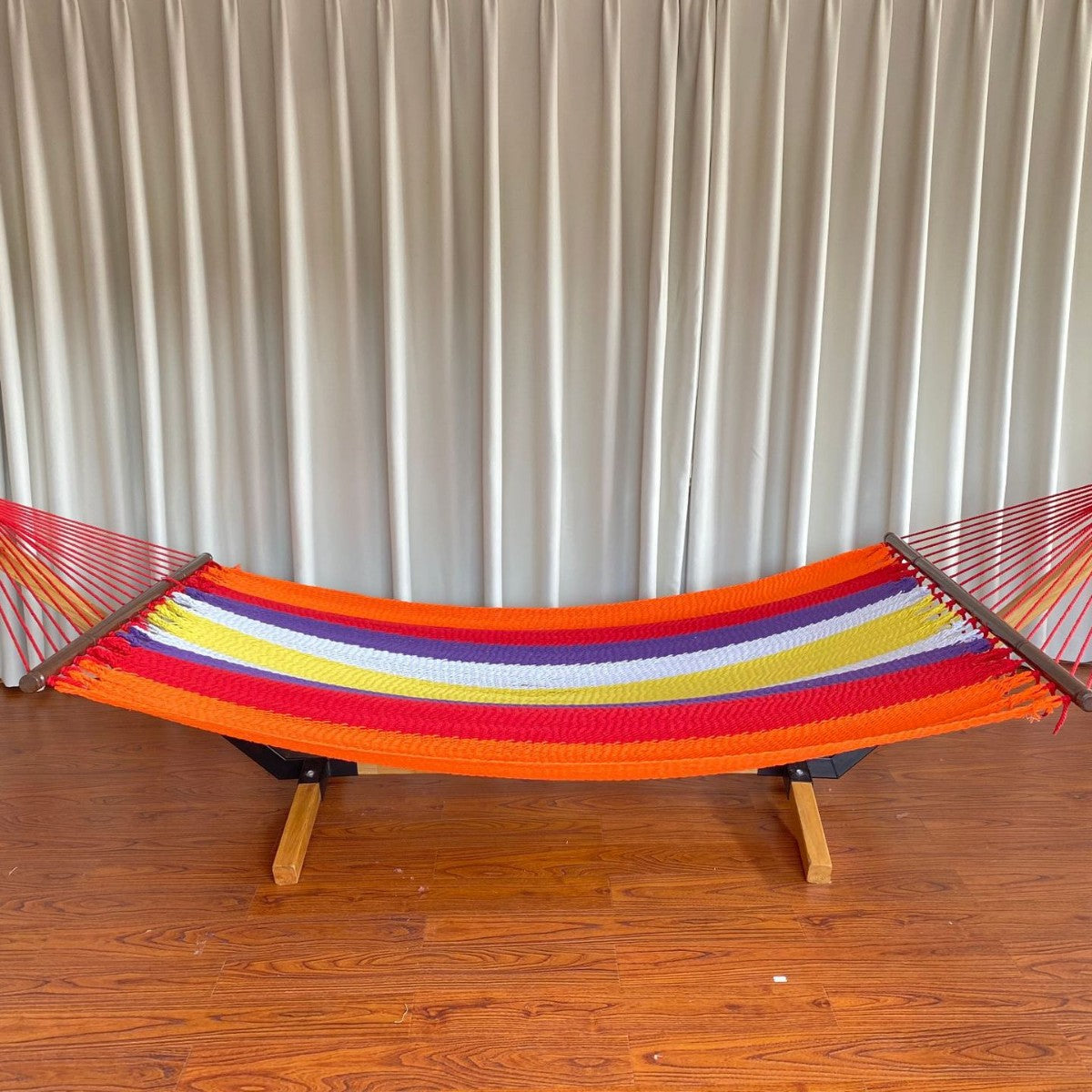 Woven cotton hammock with wooden spreader bars and freestanding stand