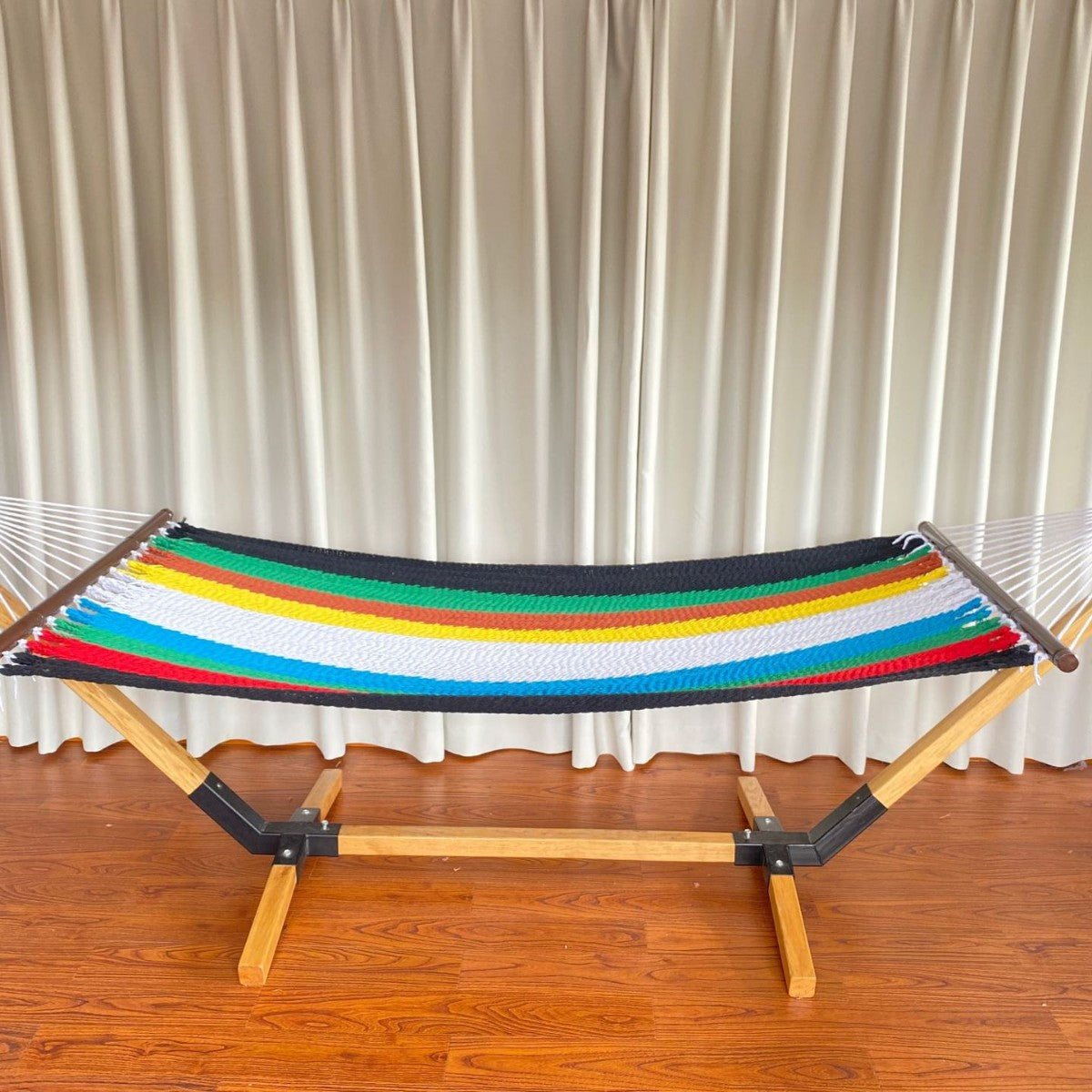 Woven cotton hammock with wooden spreader bars and freestanding stand