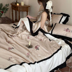Satin duvet cover set with subtly embroidered roses, contrasting piping and ruffled hem