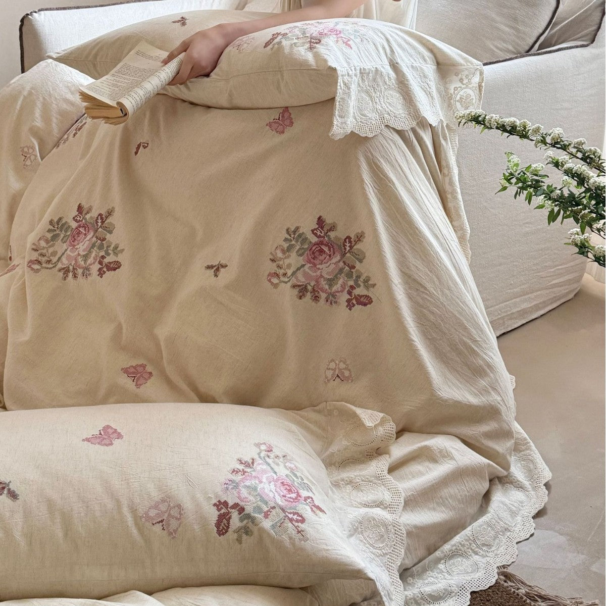 Embroidered cotton-linen bedding set with rose motifs, lace ruffle, and natural texture