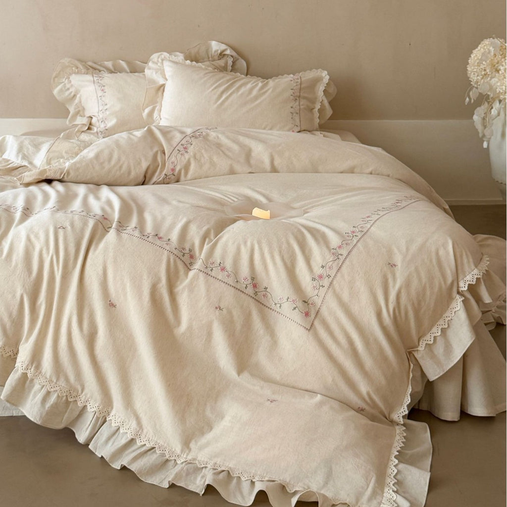 Vintage-inspired cotton bedding set with ruffles, delicate floral embroidery, and lace trim