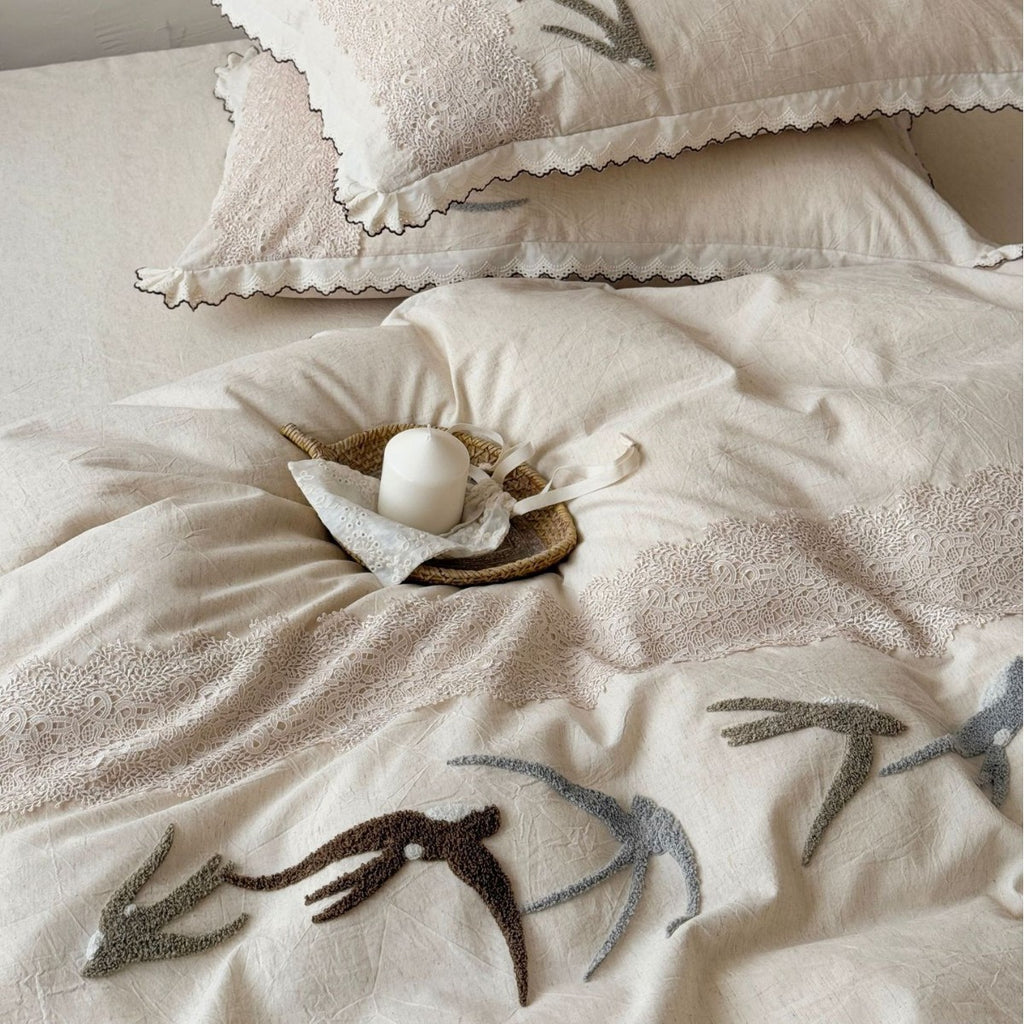 Home decor bedding set made of organic linen with hand-embroidered swallow motif and wavy hem