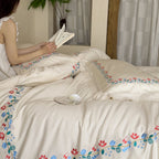 Embroidered cotton satin bed linen set with floral border and fine lace edge